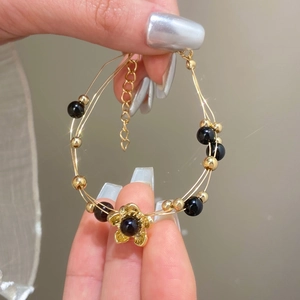 Elegante bracciale a fiori con perline oro e nere con catena regolabile da donna