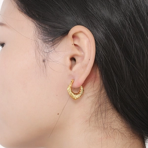 Detailed close-up of gold irregular C-shape earrings with a textured lava finish