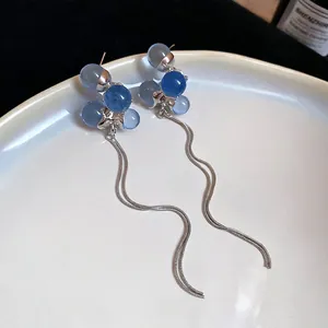Blue resin sphere earrings with silver wavy fringe tassels on a white ceramic plate