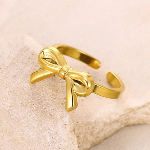 Macro shot of polished gold bow ring on a textured stone background showing fine details