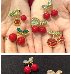 Detailed view of cherry brooches with red pearls and rhinestones on black fabric