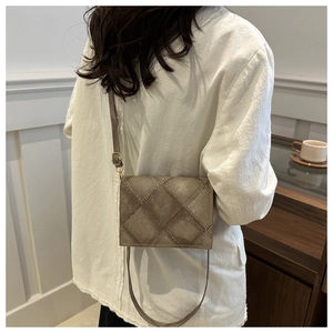 Chic quilted crossbody bag in light brown worn by a model in a minimalist interior