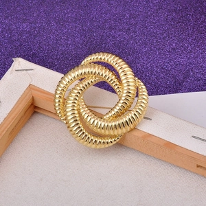 Detail of interlocking gold rings brooch with textured surface on purple background