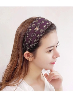 Detalle de diadema ancha de terciopelo con bordado floral dorado y adornos de pedrería
