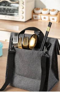 Front pocket detail of grey canvas lunch bag showing stainless steel cutlery storage