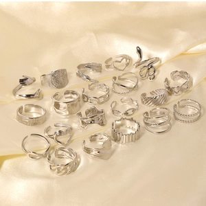 Flat lay of multiple vintage silver heart and snake design rings on champagne silk fabric