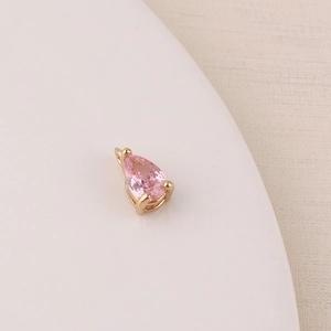 Macro shot of pink teardrop zircon pendant with gold plated three-prong setting
