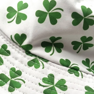 Close-up of white cotton bucket hat with green shamrock print and neat quilted stitching