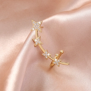 Elegant gold star ear cuff with sparkling rhinestones on a soft pink silk background