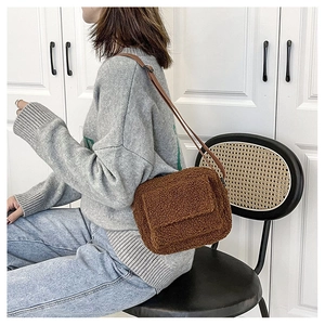 Brown faux shearling crossbody bag styled on shoulder, plush texture fashion detail view