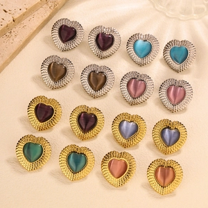 Flat lay of vintage heart-shaped stud earrings featuring cat eye stones and metallic frames