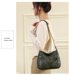 Detail of dark green PU leather crossbody bag with multiple zipper pockets on model