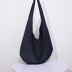 Close-up of a large dark blue denim hobo bag texture on a minimal white background
