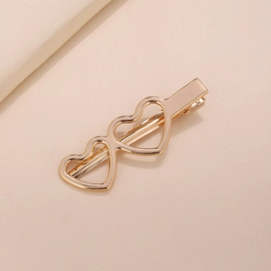 Close-up of golden interlocking hollow heart metal hair clip with polished finish