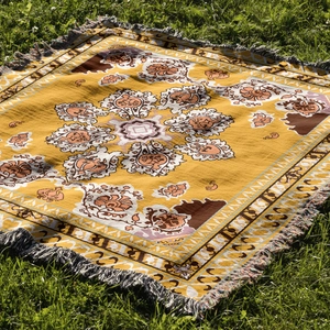 Close-up of yellow bohemian mandala picnic blanket with long fringe tassels on grass