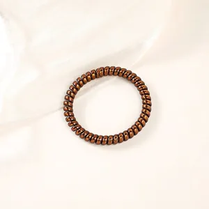 Detailed view of bronze spiral telephone wire hair tie with metallic glossy finish