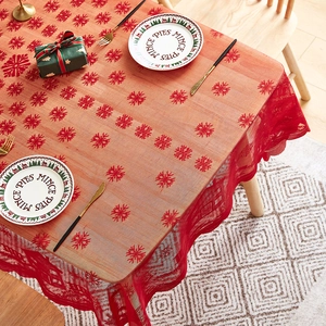 Detailed view of red Christmas tablecloth with snowflake and house patterns on wood table