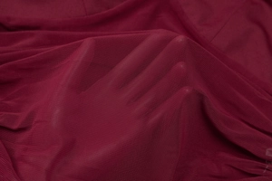 Gros plan sur la texture en maille bordeaux montrant les détails du tissu transparent