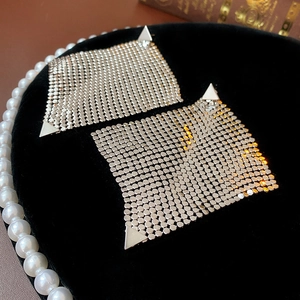 Detailed view of silver mesh drop earrings on black velvet with elegant pearl accents
