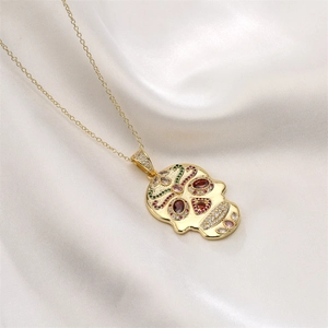 Detailed view of a gold skull pendant necklace with multi-colored zircon stones on silk