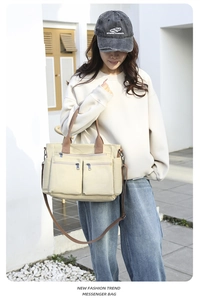 Detail der beige Leinwand Kuriertasche mit Reißverschlusstaschen und braunen Riemen
