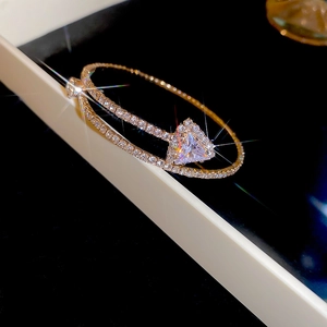Macro view of gold double-layer bangle with a sparkling triangle zircon and pavé setting