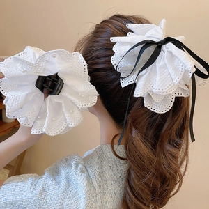 Detailansicht der eleganten weißen Spitzen-Haarklammer mit Perlen und schwarzer Schleife