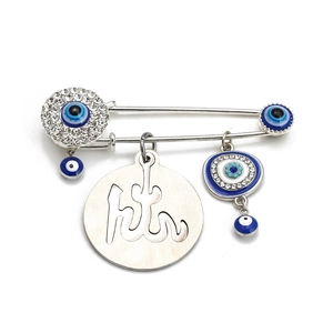 Macro detail of silver Evil Eye brooch with sparkling crystals and Arabic calligraphy pendant