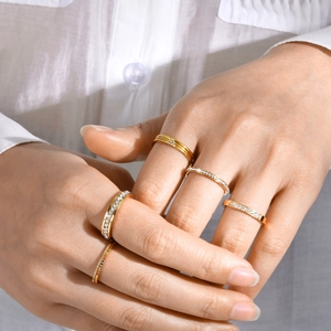 Detail of stacked gold stainless steel rings with colorful zircon inlay on model hand