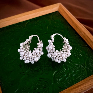 Close-up of French vintage silver hoop earrings with white faux rice pearls on a green tray