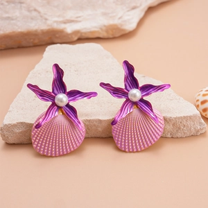 Detail of starfish and shell earrings with pearls on a natural stone surface