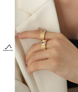 Detail of 18K gold plated stainless steel rings with zircon stones on a white blazer