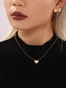 Close-up of golden heart necklace and earrings set with white mother of pearl inlay