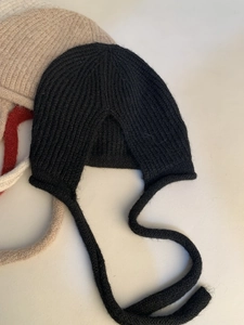 Dettaglio della maglia a coste in misto lana e dei lunghi lacci del cappello invernale