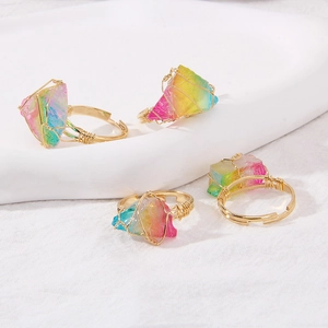 Detailed close-up of four handmade wire-wrapped rings with iridescent raw crystals