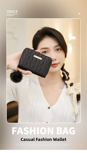 Detail of black quilted leather wallet with gold metal bar and soft pompom charm