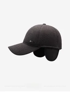Macro detail of dark brown wool texture and metal logo plaque on earflap winter cap
