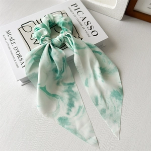 Detail of light green tie-dye chiffon scrunchie with streamer on a Picasso book