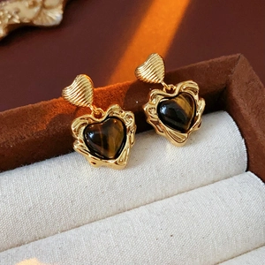 Detail of gold-plated heart earrings with tiger eye stone in a luxury jewelry box