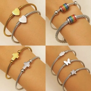 Detailed macro view of four ethnic steel wire spiral bangles with various heart and cross charms