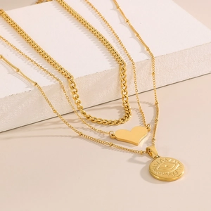 Dettaglio della collana dorata a strati con ciondolo a cuore e amuleto a forma di occhio