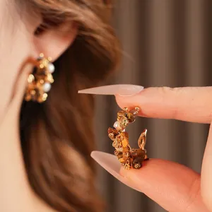 Vintage gold C-shaped earrings with tiger eye stone and pearls shown on a model