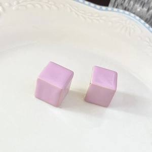 Détail de boucles d'oreilles fleurs roses sur une assiette blanche gaufrée