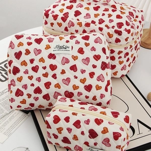 Three sizes of quilted cosmetic bags with red heart patterns for travel storage