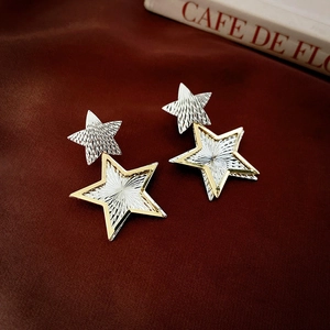 Detail of star-shaped earrings with radial texture on brown silk fabric background