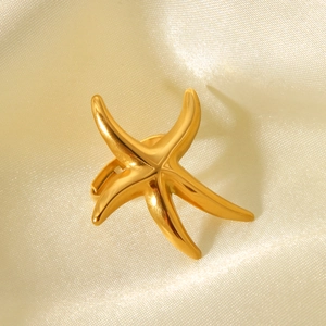 Detailed view of a gold starfish ring with a polished finish on cream silk fabric