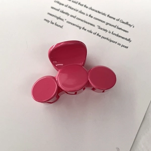 Macro detail of glossy magenta hair claw clip featuring three circular resin structures