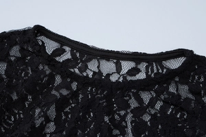 Close-up detail of the elegant black lace floral pattern and round neckline on the dress