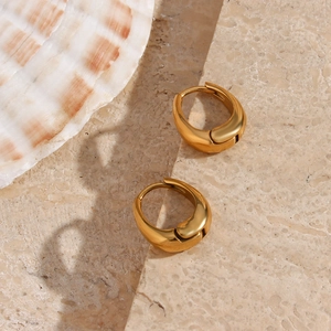 Macro shot of 18K gold plated tear-drop hoop earrings on elegant marble and shell surface