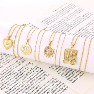 Detailed shot of four gold tarot-style necklaces with cubic zirconia on a book page